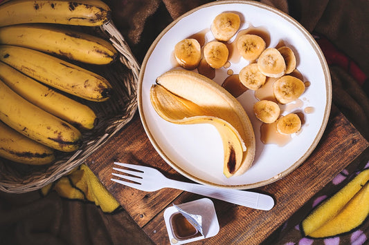 Stack of golden banana pancakes topped with colorful microgreens and sliced bananas