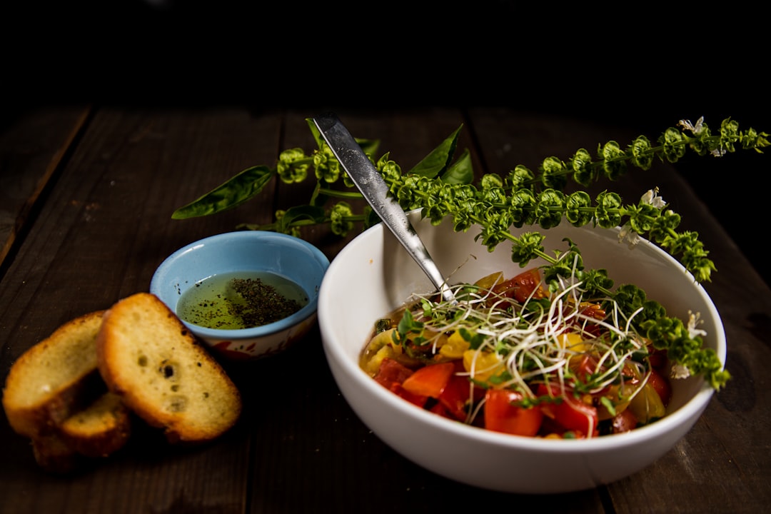 Bowl of pasta primavera topped with fresh pea shoot microgreens and shaved parmesan on a wooden table