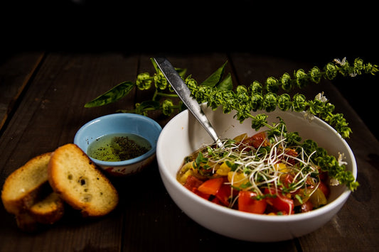 Bowl of pasta primavera topped with fresh pea shoot microgreens and shaved parmesan on a wooden table