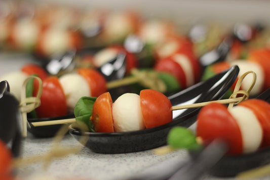 Caprese skewers with fresh mozzarella, cherry tomatoes, basil, and sunflower microgreens on a white serving platter