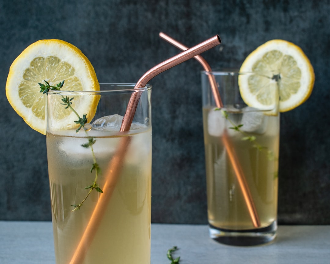 Two glasses of herbal iced tea garnished with sunflower microgreens on a wooden table