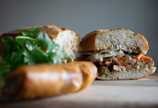 Vietnamese banh mi sandwich loaded with colorful microgreens and pickled vegetables on crusty bread