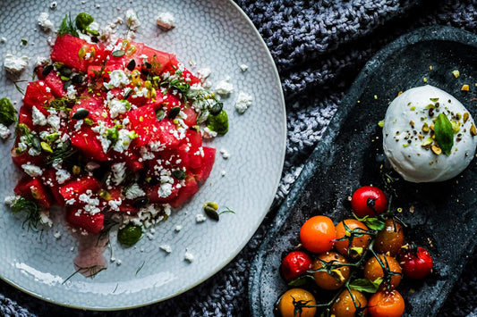 Colorful watermelon feta salad with microgreens in white bowl on wooden table