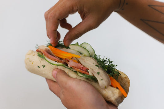 BLT sandwich with microgreens on rustic wooden cutting board