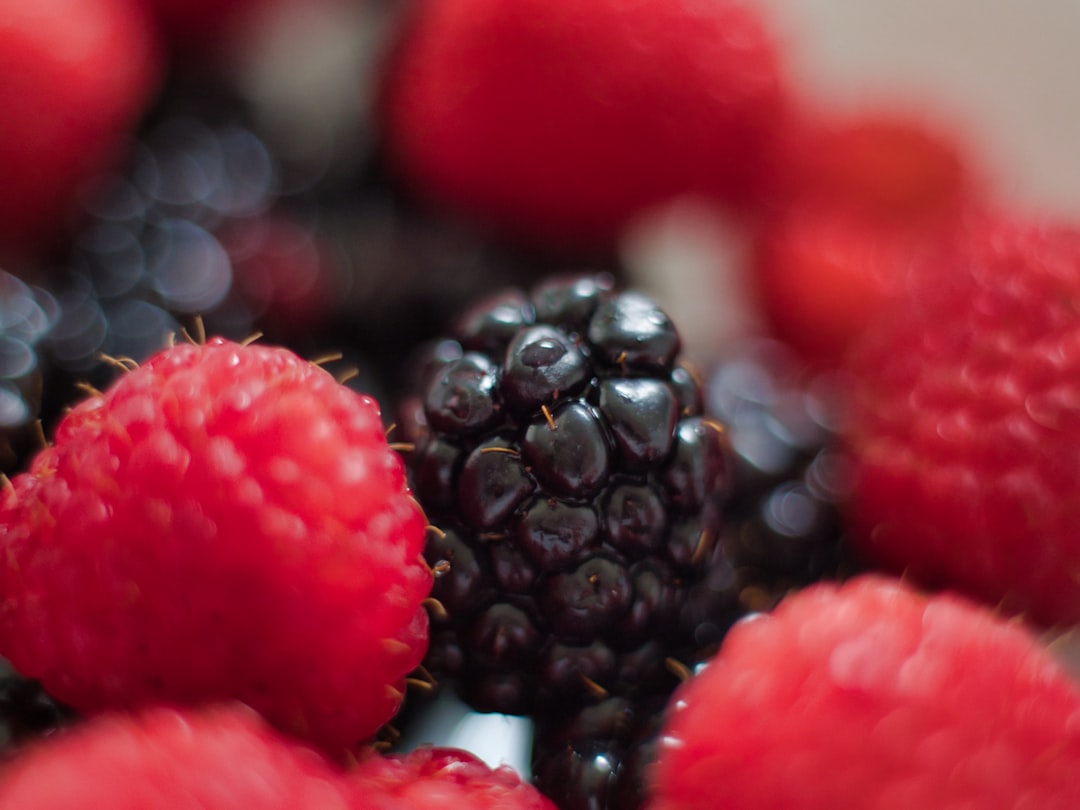Purple berry smoothie topped with fresh microgreens in glass with berries scattered around