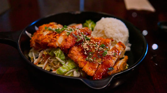 Teriyaki salmon bowl topped with sunflower microgreens, pickled cucumber, and sesame seeds on a white rice base